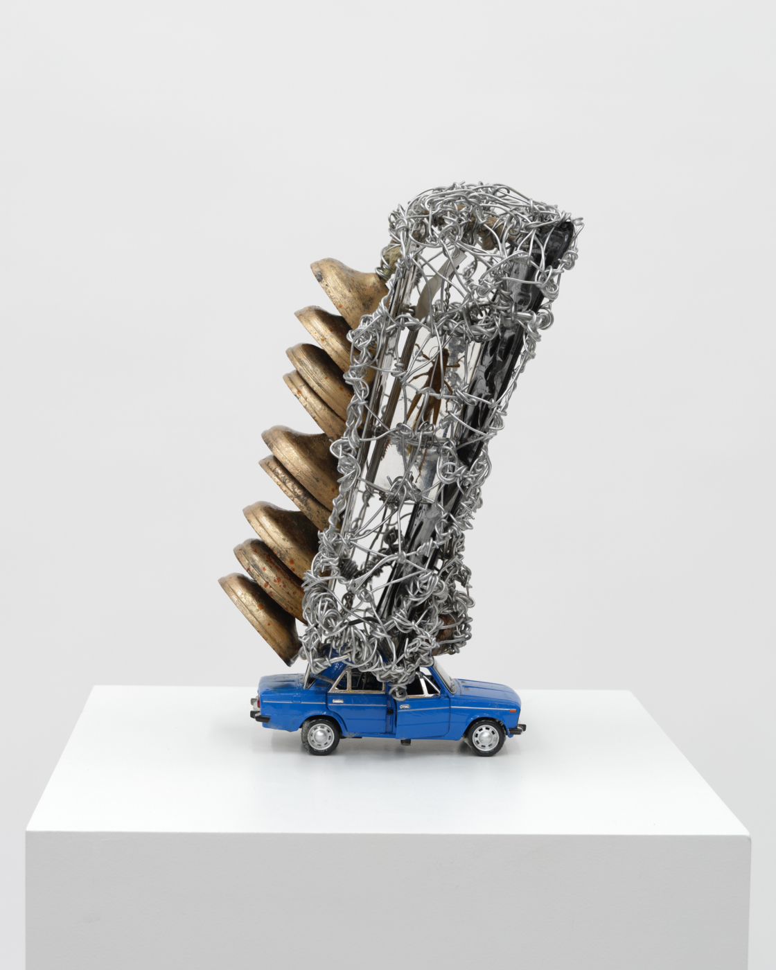 Insect in The Wall, 2024. Wire, metal, bells, license plates, insect, toy car and rope, 14 x 8 x 8 in. (35.56 x 20.32 x 20.32 cm)